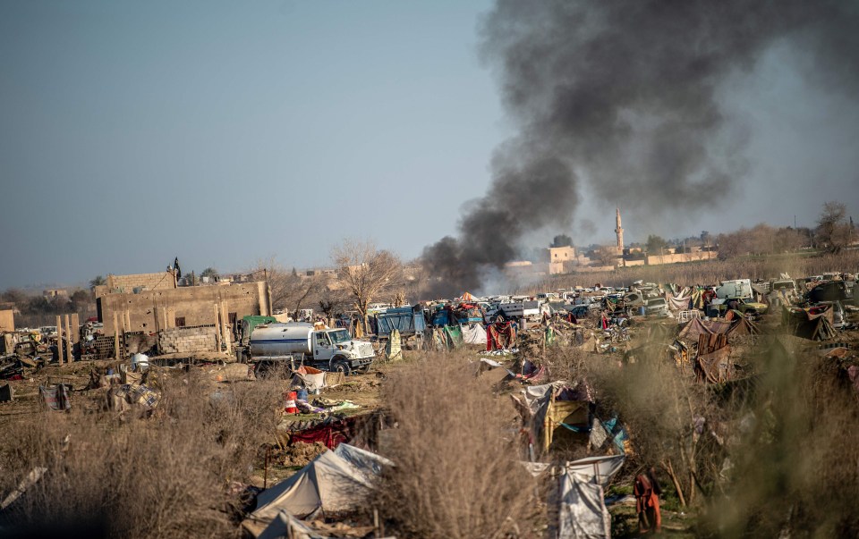 Smoke rises from a makeshift camp for ISIS members and their families in Baghouz,. Thousands of people, mostly women and children, have fled over the past days but it’s feared several brainwashed people remain inside