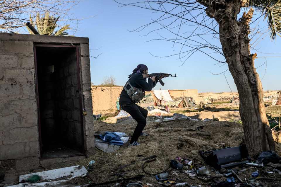  A fighter with the Syrian Democratic Forces (SDF) takes aim with his Kalashnikov assault rifle after seeing a man walking towards his position in the town of Baghouz