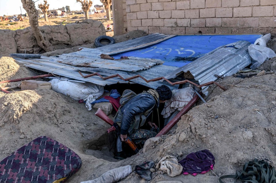 A fighter with the Syrian Democratic Forces (SDF) inspects makeshift shelter dug in a trench at a makeshift camp for Islamic State members and their families in the town of Baghouz