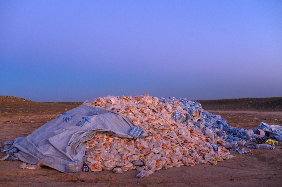 A pile of food aid containing bread and water bottles is left in the desert for civilians from the town of Baghouz