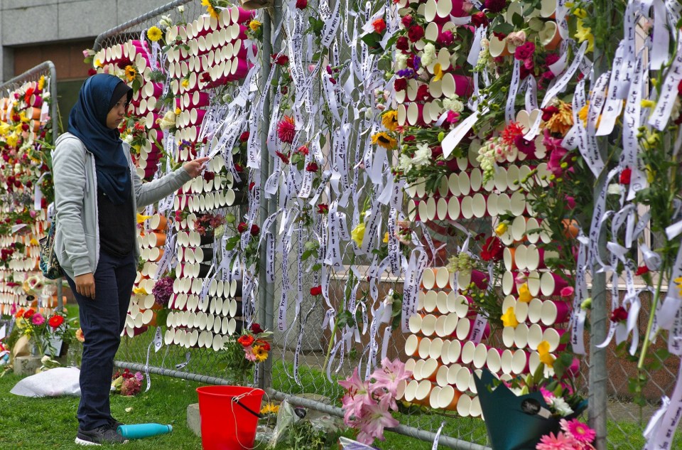 A student views tributes hung on wire fences in tribute to the victims of twin shooting attacks targeting Al Noor and Linwood mosques in Christchurch