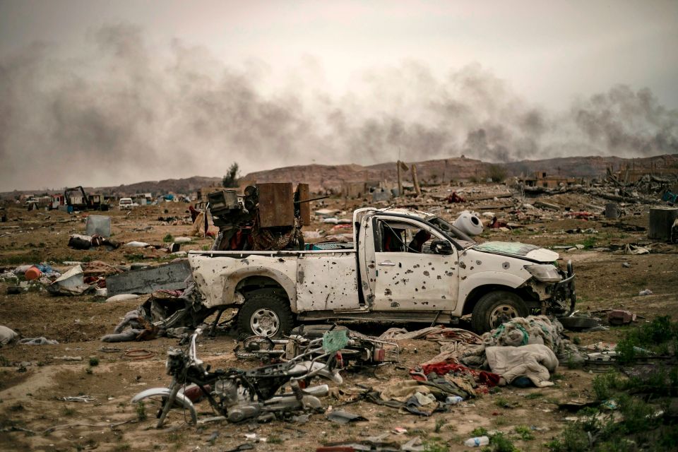  Smoke rises in front of a machine gun carrying pick-up ridden with bullets