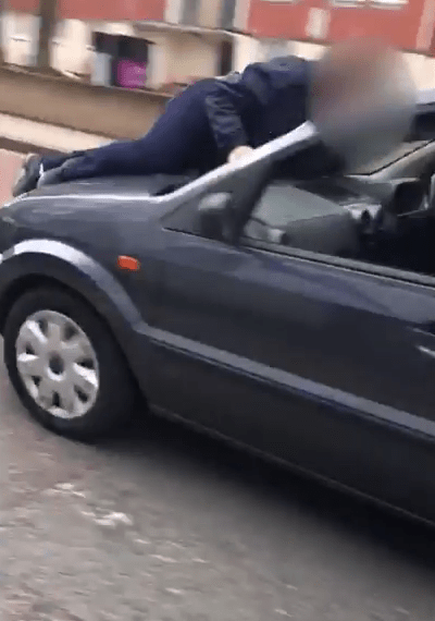  One of the attackers jumps on the bonnet of a moving car after worshippers give chase