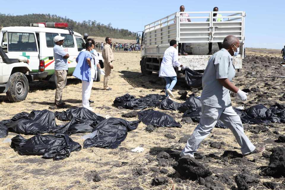  Rescue workers walk past body bags at the crash site