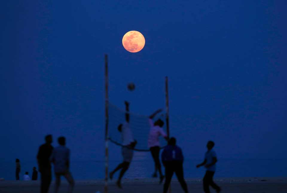  Friends playing volleyball beneath the pink moon near Kuwait City