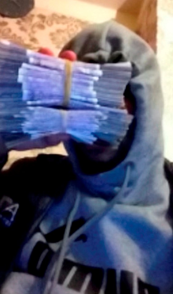  A member of the gang held a pile of notes to hide their face