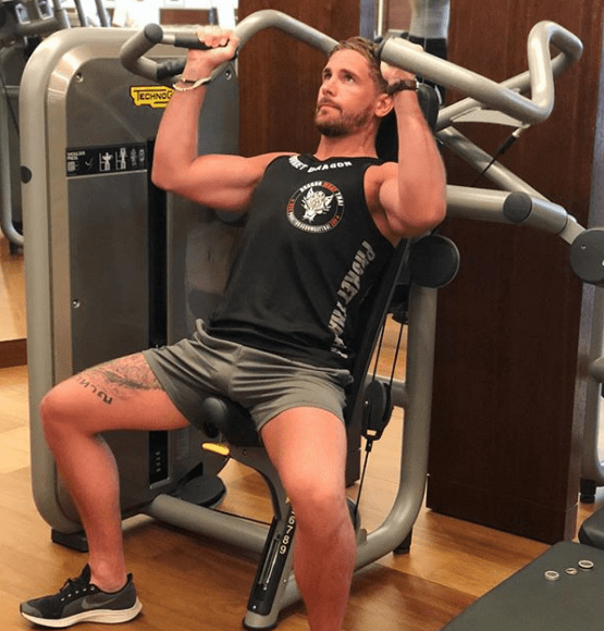 Adam Woodward working out on a shoulder press machine.