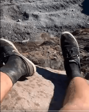 The male backpacker dangled his legs over the edge of the spout