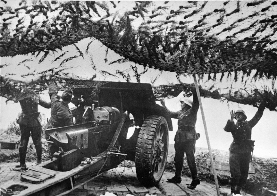  A German crew position the camouflage net over a captured French 105 mile 1913 Schneider gun that has been sited to cover a possible landing site on the French coast