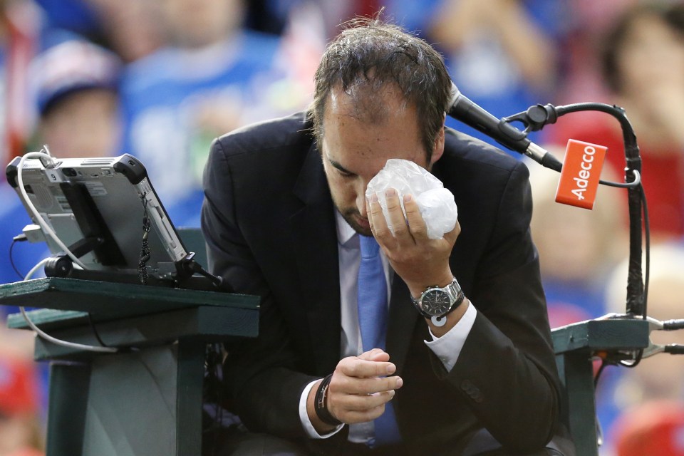 Umpire Arnaud Gabas holds an ice pack to his eye after being struck by a ball in 2017