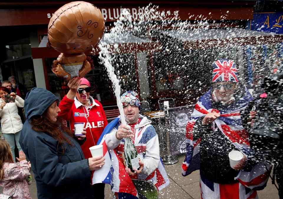  Royal super fans pop the cork on a bottle of champagne, as they stand near Windsor Castle after hearing the news