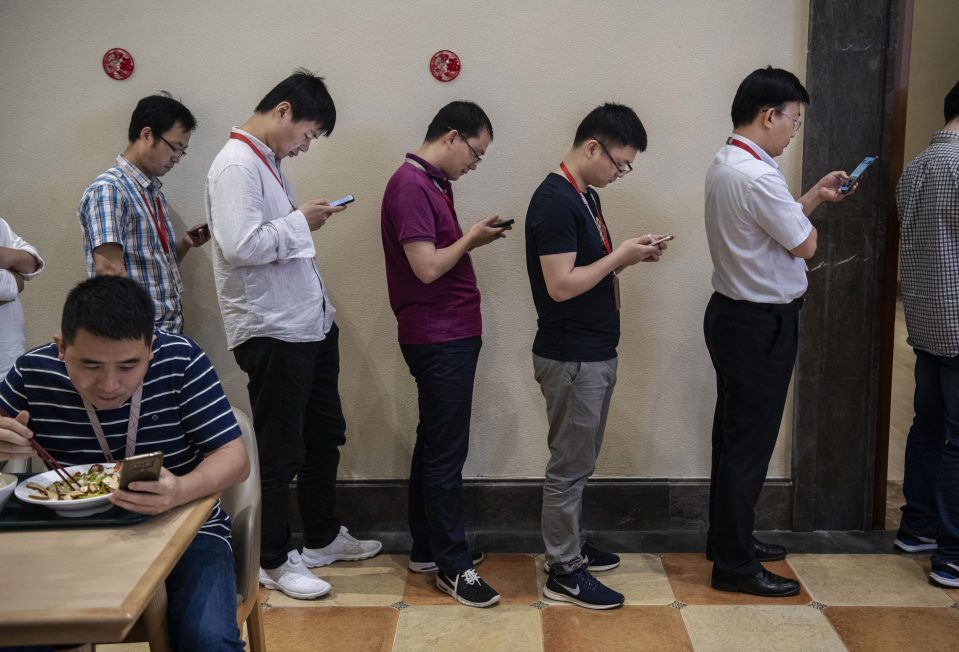  Young employees can be seen glued to their smartphones as they queue for food