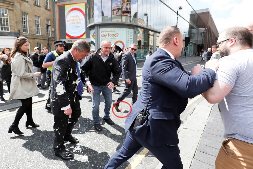  A security guard pushes Crowther out of the way after the milkshake was thrown, with the empty cup seen circled here