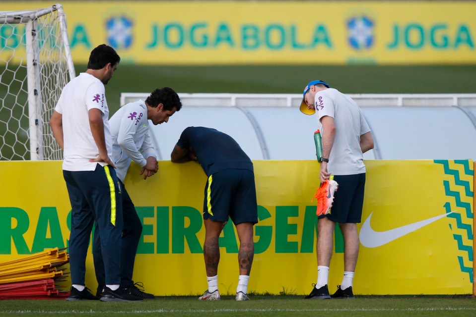  Neymar slumped over an advertising hoarding as he was spoken to by medical staff