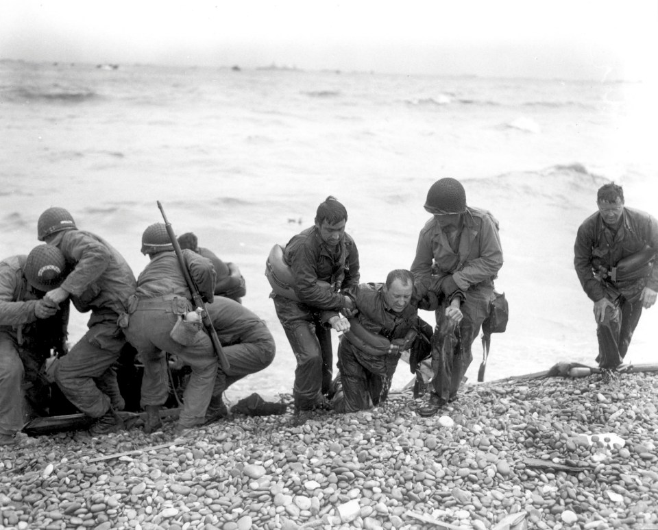  Members of an American landing party assist troops whose landing craft was sunk by enemy fire off Omaha beach, near Colleville sur Mer, France, June 6, 1944