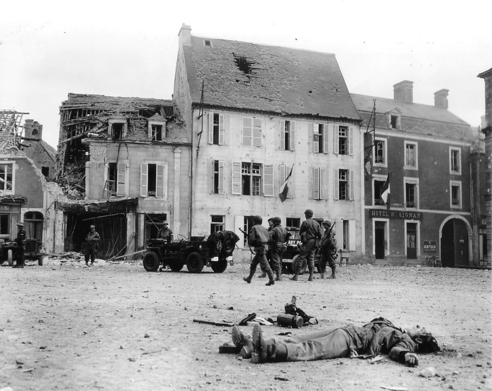  The body of a dead German soldier lies in the main square of Place Du Marche after the town was taken by US troops