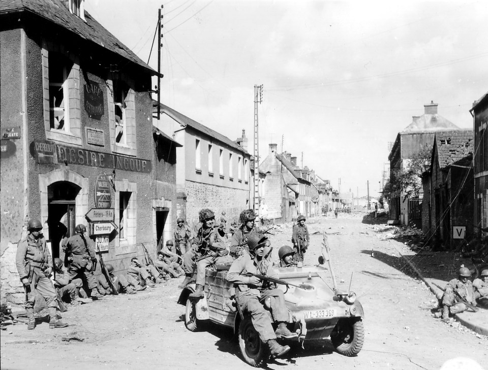  US Army paratroopers of the 101st Airborne Division drive a captured German Kubelwagen on D-Day at the junction of Rue Holgate and RN13 in Carentan, France, June 6, 1944