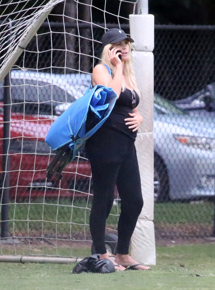  Elin Nordegren places a hand on her baby bump as she watches her son play flag football in Florida