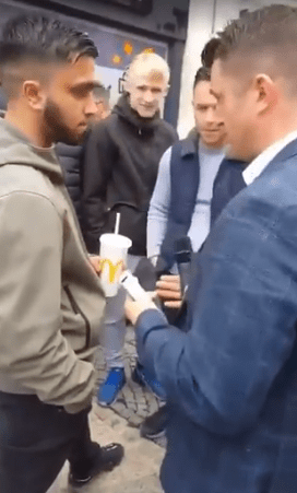  Robinson is surrounded by smirking supporters as he confronts one lad who then calmly lobs a strawberry shake over his face