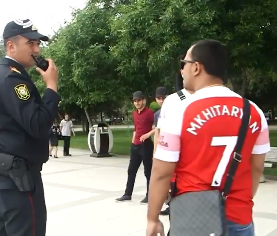  A police officer spoke into a walkie-talkie as he stopped the two Gunners supporters