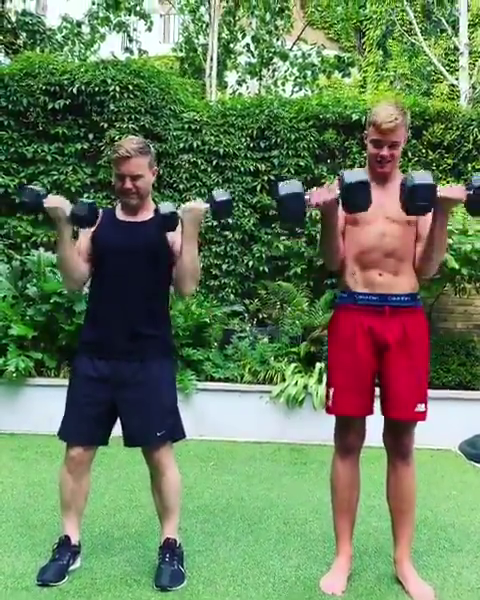 a man and a boy are lifting dumbbells in a garden .