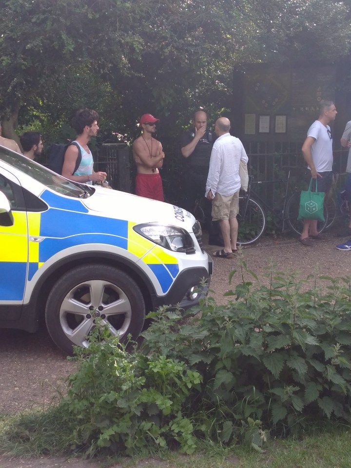  Bathers stand at the edge of the pond while emergency services search for the missing bather