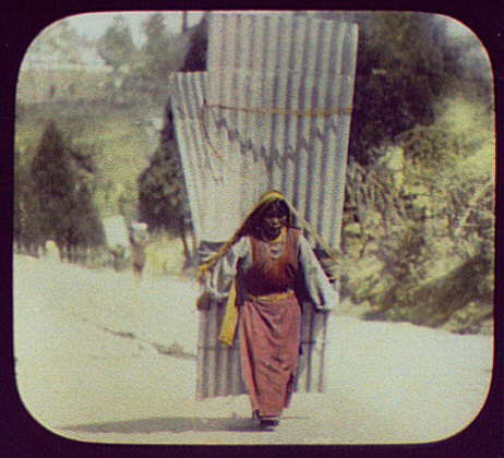  A woman carries a heavy load of corrugated metal