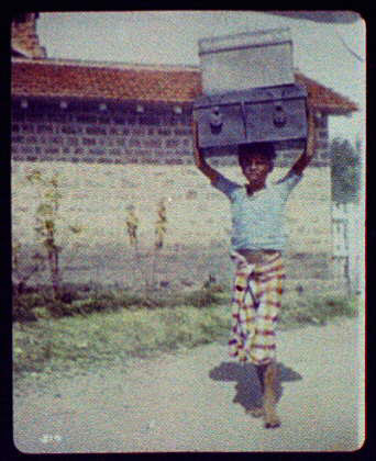  A young boy carries two heavy trunks in Delhi