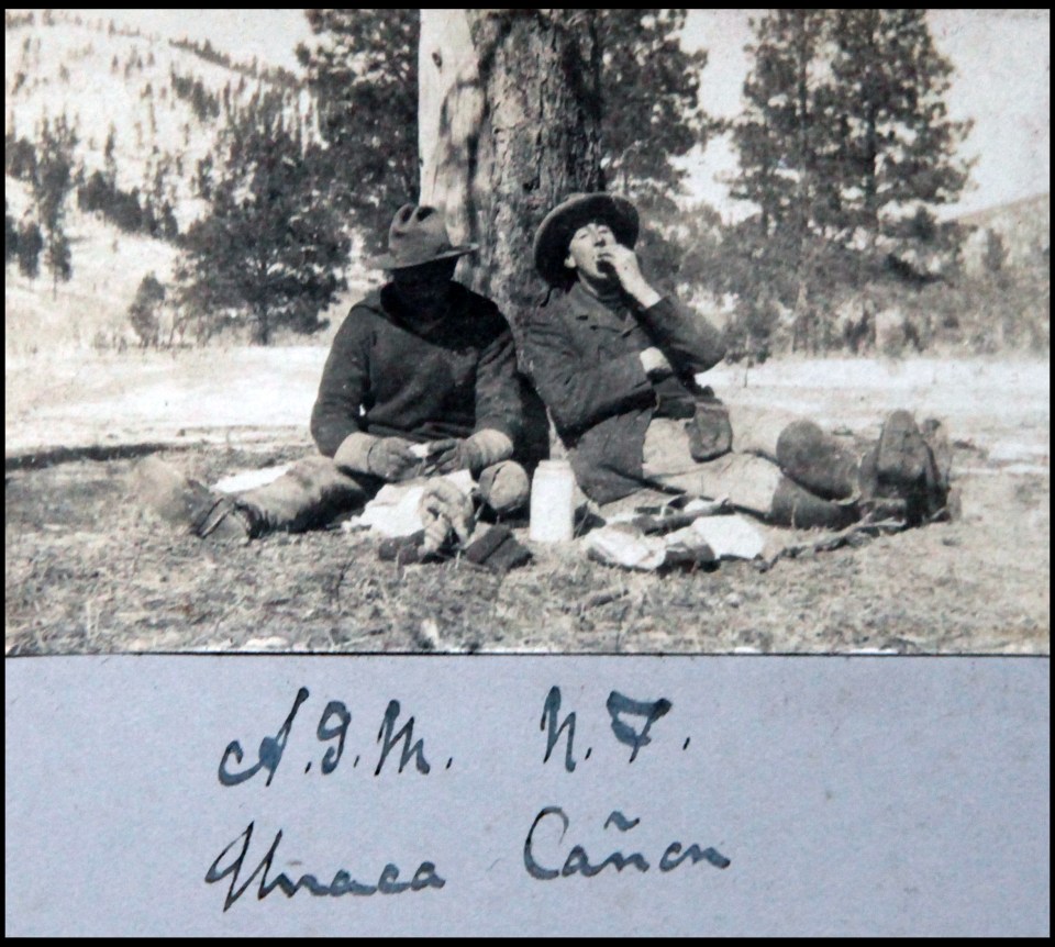  Two cowboys relax against a tree after a hard day's work