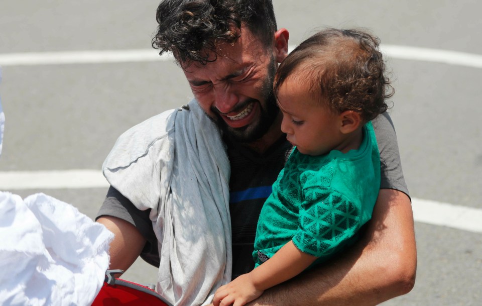  A father holds his child after being stopped by Mexican immigration authorities