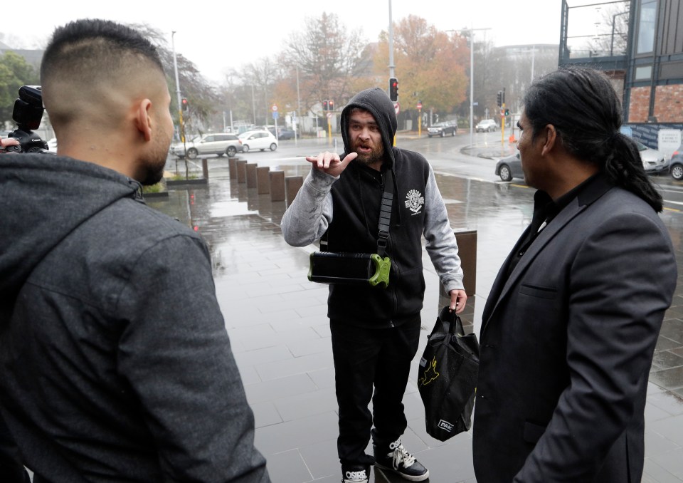  A man, centre, argues with survivors of the attack outside the courtroom