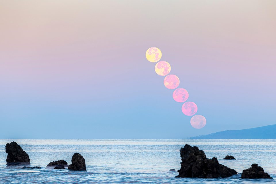 The Strawberry Moon in stages setting behind the island of La Gomera in Spain's Canary Islands, viewed from Tenerife