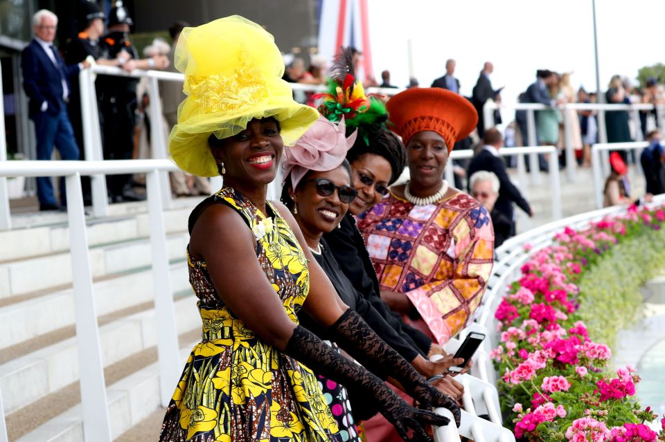 Racegoers in colourful patterns and bright hats smile during the first day of the Royal Ascot