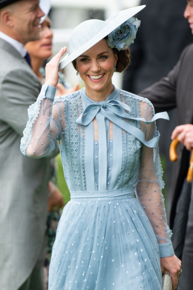 Kate holds on to her hat as she greets members of the royal family