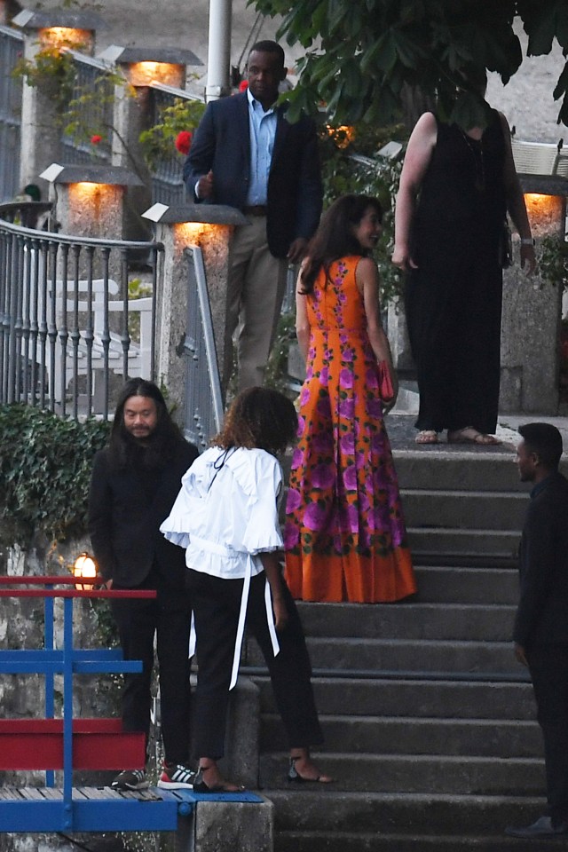  Their wives Michelle, (in white) and Amal (in orange) were also snapped ascending the stairs to the villa