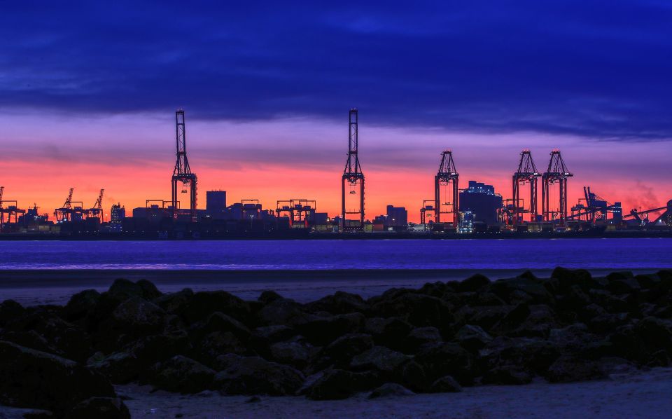 The orange colours of the sunrise appear through the blue colours of dawn over the Liverpool docks