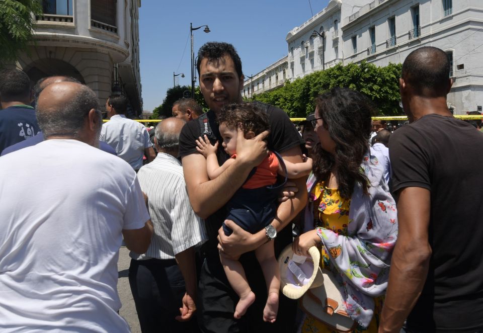  A man carrying his child near the scene of the blast in the centre of Tunis