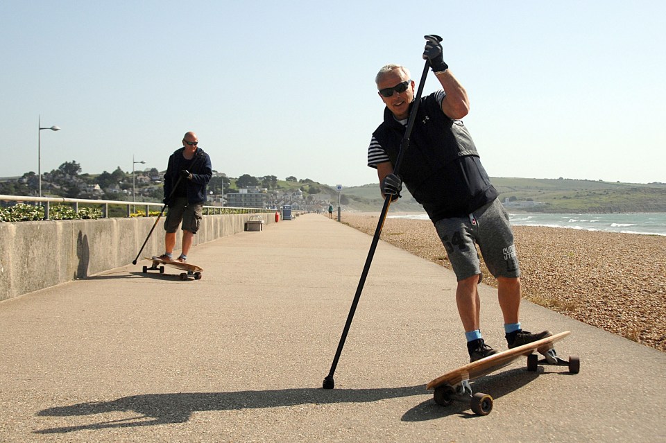 Two men go long boarding along Preston Beach in Weymouth 