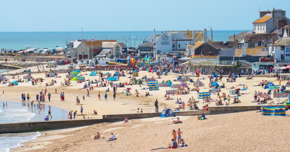 Sunbathers flock to the beach at the seaside resort of Lyme Regis in Dorset to enjoy a day of clear blue skies and scorching sunshine