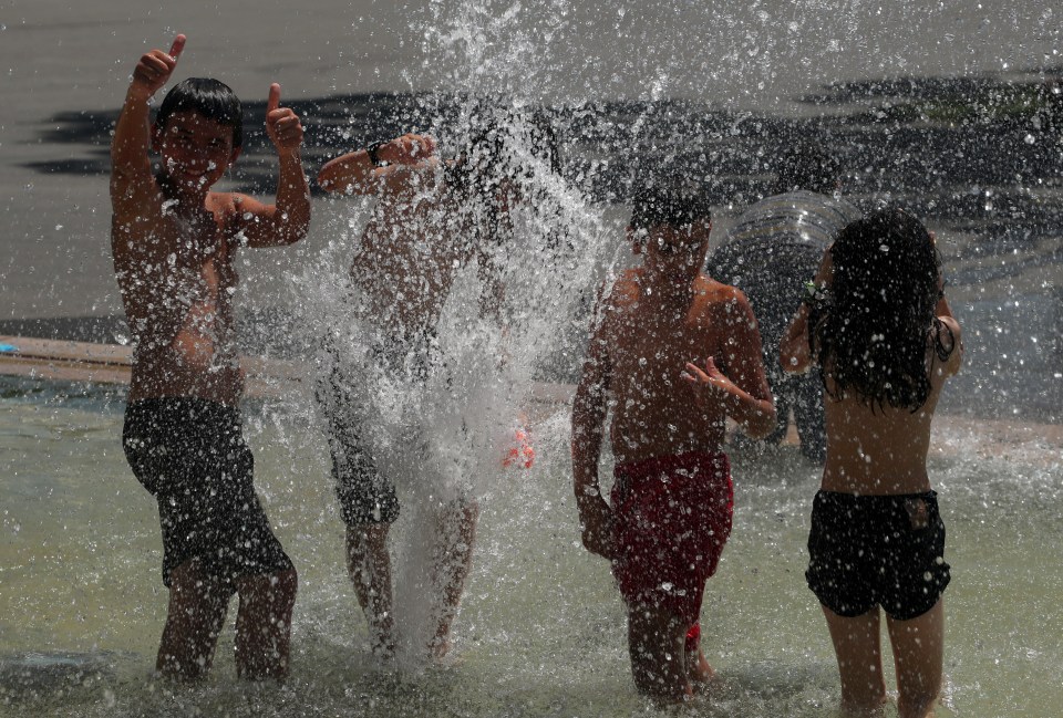  Teenagers play in a fountain during a heatwave in Lausanne, Switzerland