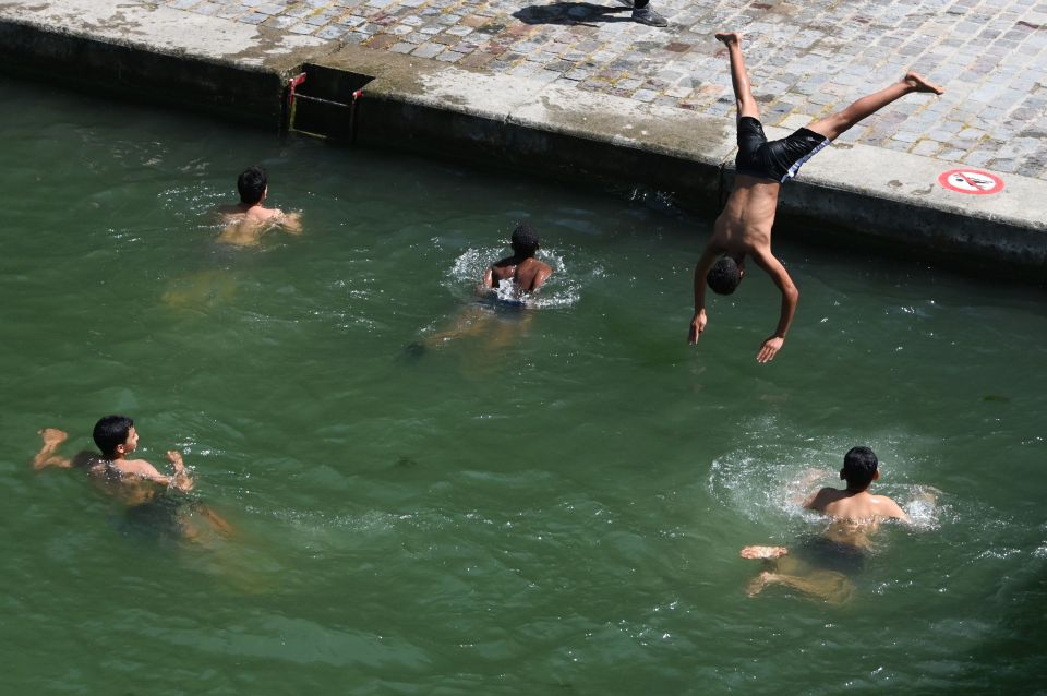  A man dives into the waters of the Canal Saint-Martin in Paris as forecasters warn the 'worst is yet to come'