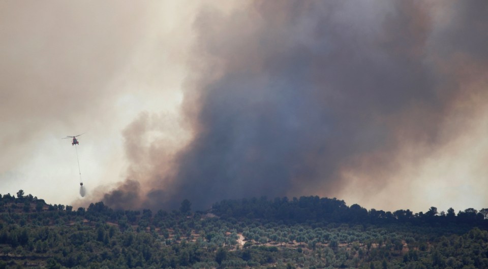  A helicopter drops water over a fire during a forest fire near Bovera, west of Tarragona, Spain