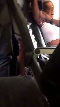 In this footage, a woman is seen being held down by passengers as she sobs