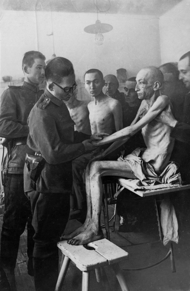  A physician inspects the body of a victim at a concentration camp in 1945