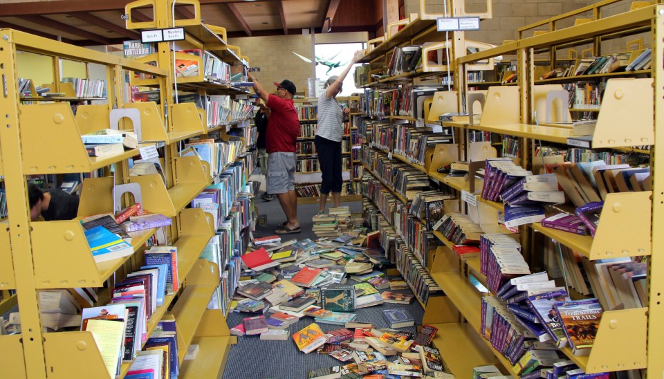 Volunteers work to put books back on the shelf after they were sent flying