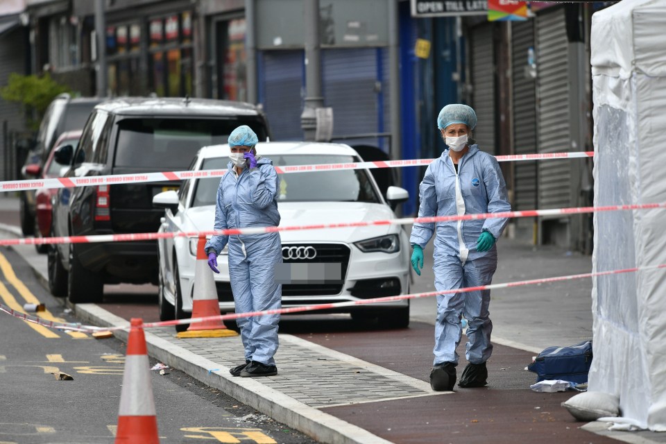  Forensic officials investigate the scene where a man in his 20s was fatally shot in Leyton