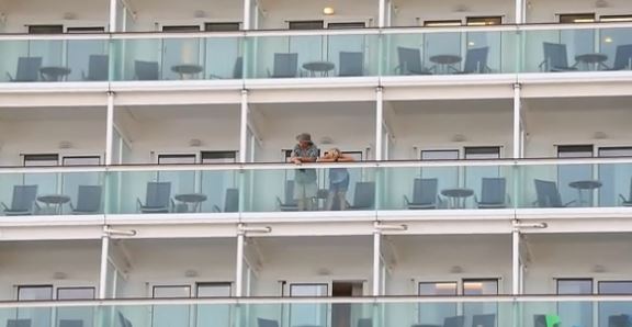  Passengers aboard the vessel look over a balcony