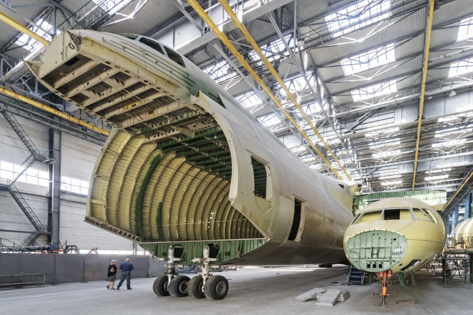  Workers walk past the hull of a mothballed Antonov An-225 cargo aircraft in a hangar at the Antonov Co. manufacturing facility