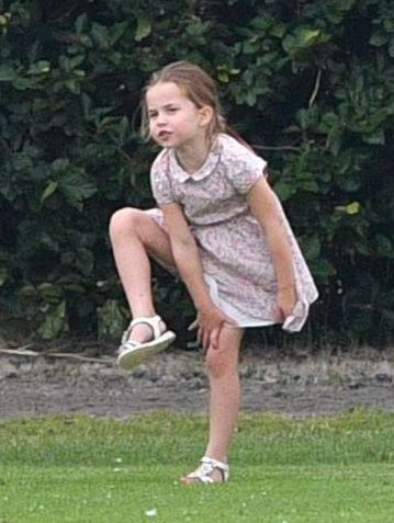 Princess Charlotte stands on one foot as she plays football with her big brother