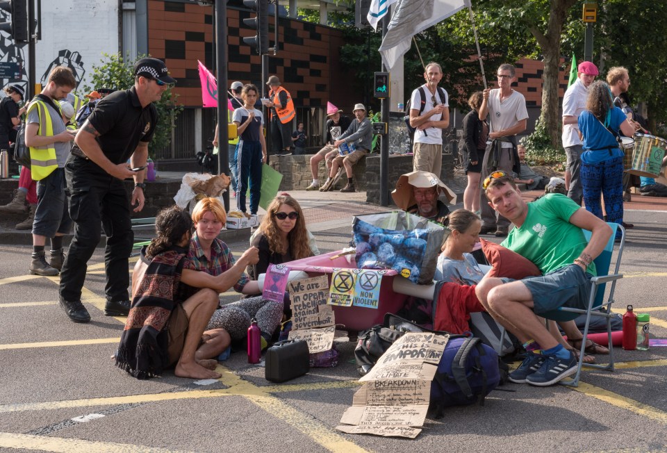 Campaigners locked themselves onto a pink bath tub as Extinction Rebellion blocked a major road junction at morning rush hour in Bristol on July 17